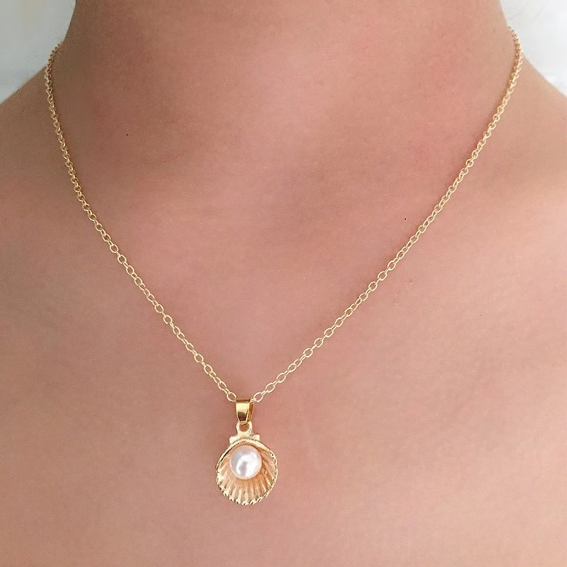 Gold-tone shell and pearl pendant necklace, photographed worn.